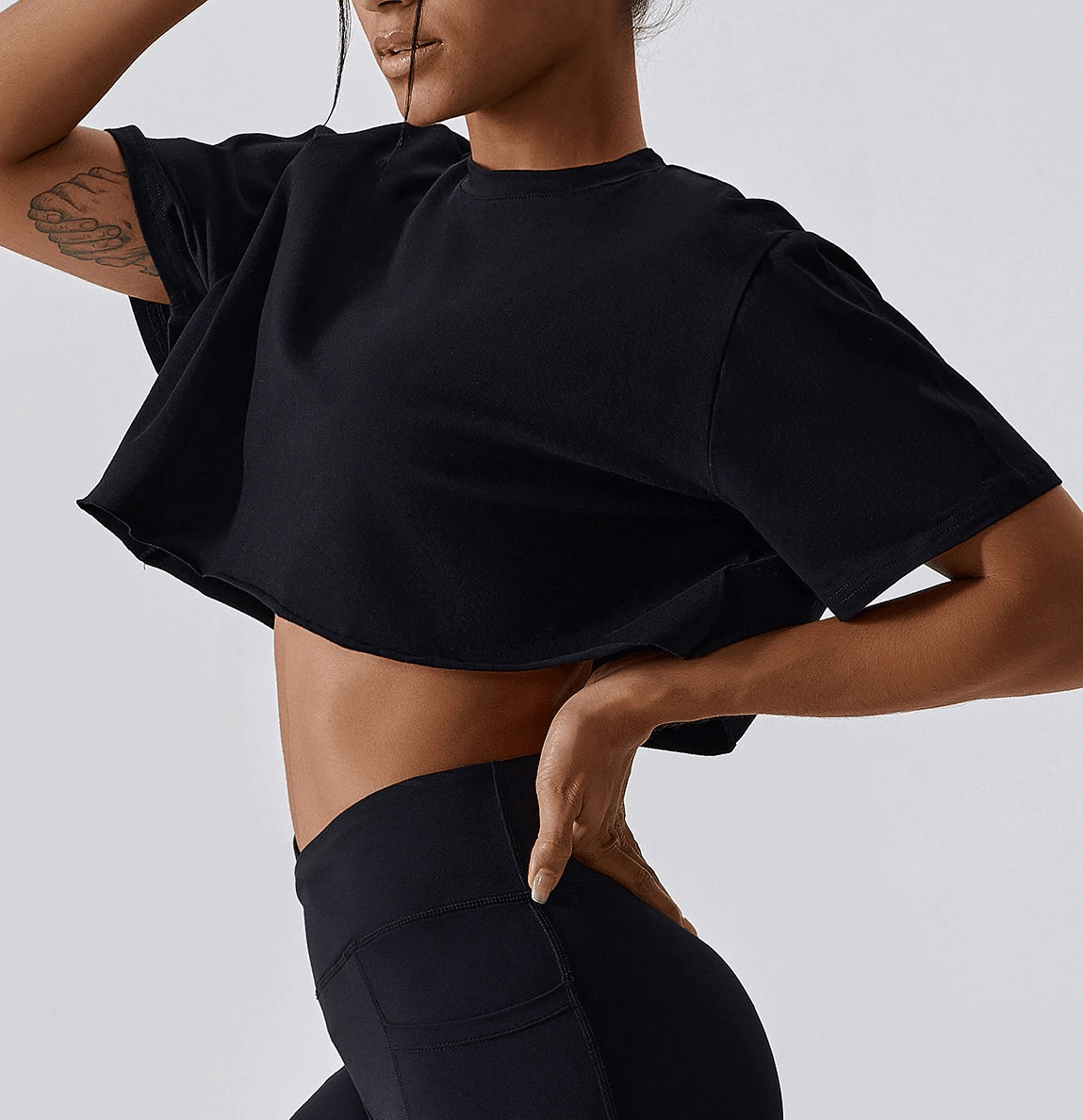 Woman wearing black sports loose crop top, perfect for yoga, running, and dance, showcasing comfortable and stylish design ideal for workouts.